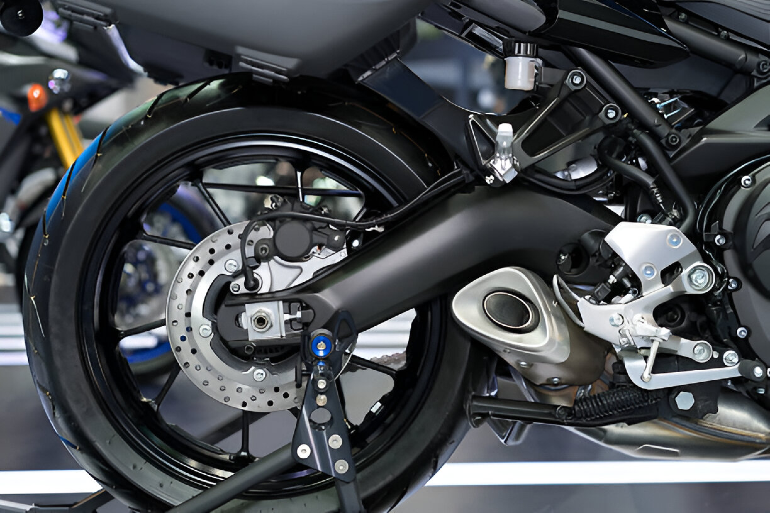 Close-up view of a modern motorcycle's rear wheel, showing the braking system and exhaust design, ideal for understanding engine braking mechanics on bikes.